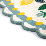 close up of An small oval scalloped rug with strawberry and floral motifs