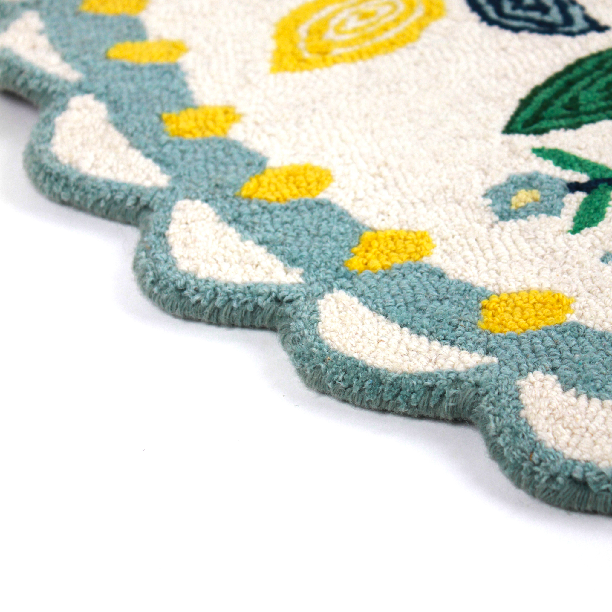 close up of An small oval scalloped rug with strawberry and floral motifs