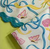 A close up of Bunnies and bow print fabric easter napkins in multicolor against a light green background. 