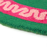 close up of a round green and pink rug with a central red and pink lobster motif.