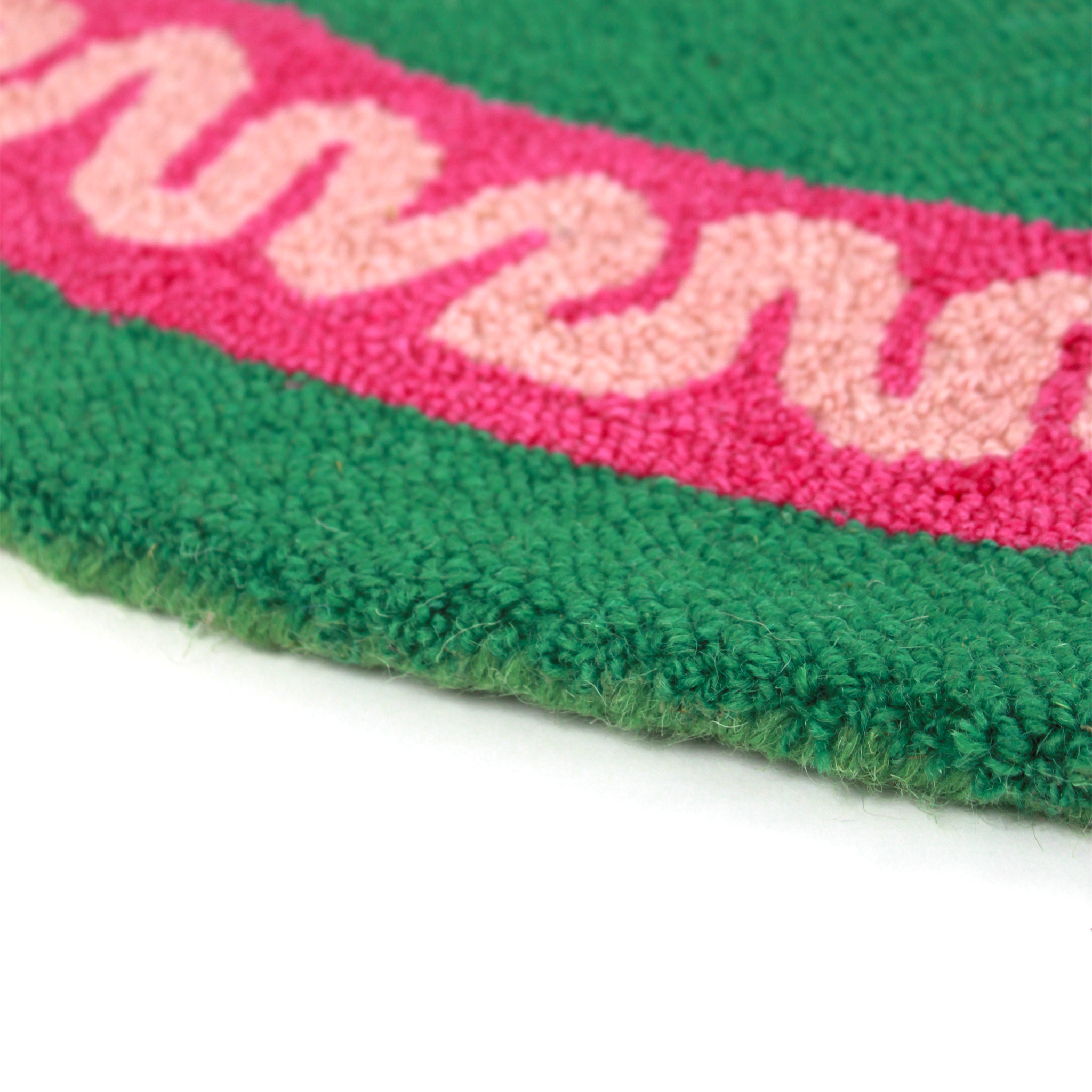 close up of a round green and pink rug with a central red and pink lobster motif.