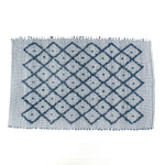 A blue accent rug with a diamond pattern on it