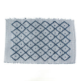 A blue accent rug with a diamond pattern on it