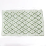 A green accent rug with a diamond pattern on it
