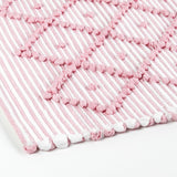 A close up look of a pink accent rug with a diamond pattern on it