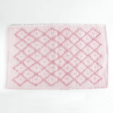 A pink accent rug with a diamond pattern on it