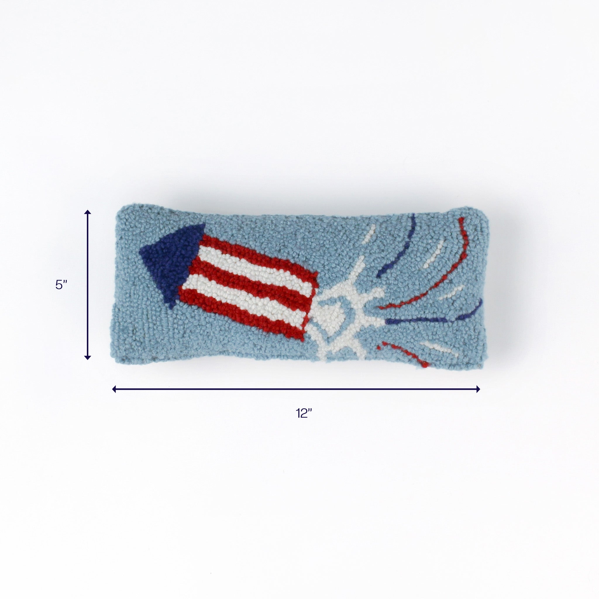 Light blue rectangular pillow with a red-white rocket design and fireworks, 12 inches by 5 inches.