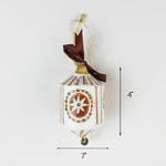 White and gold holiday ornament with star design and ribbon, approximately 4 inches tall and 7 inches wide.