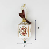 White and gold holiday ornament with star design and ribbon, approximately 4 inches tall and 7 inches wide.