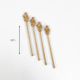 Set of four gold drink stirrers with decorative tops, each measuring 8.5 inches long.