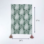 Green and white patterned table runner with tassels on both ends shown with 24 inch length and 17 inch height.