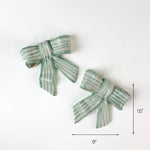 Set of two green striped ceramic bows, each 6 inches wide.
