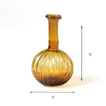 Amber glass bottle with ribbed round base, 5 inches tall and 3 inches wide.