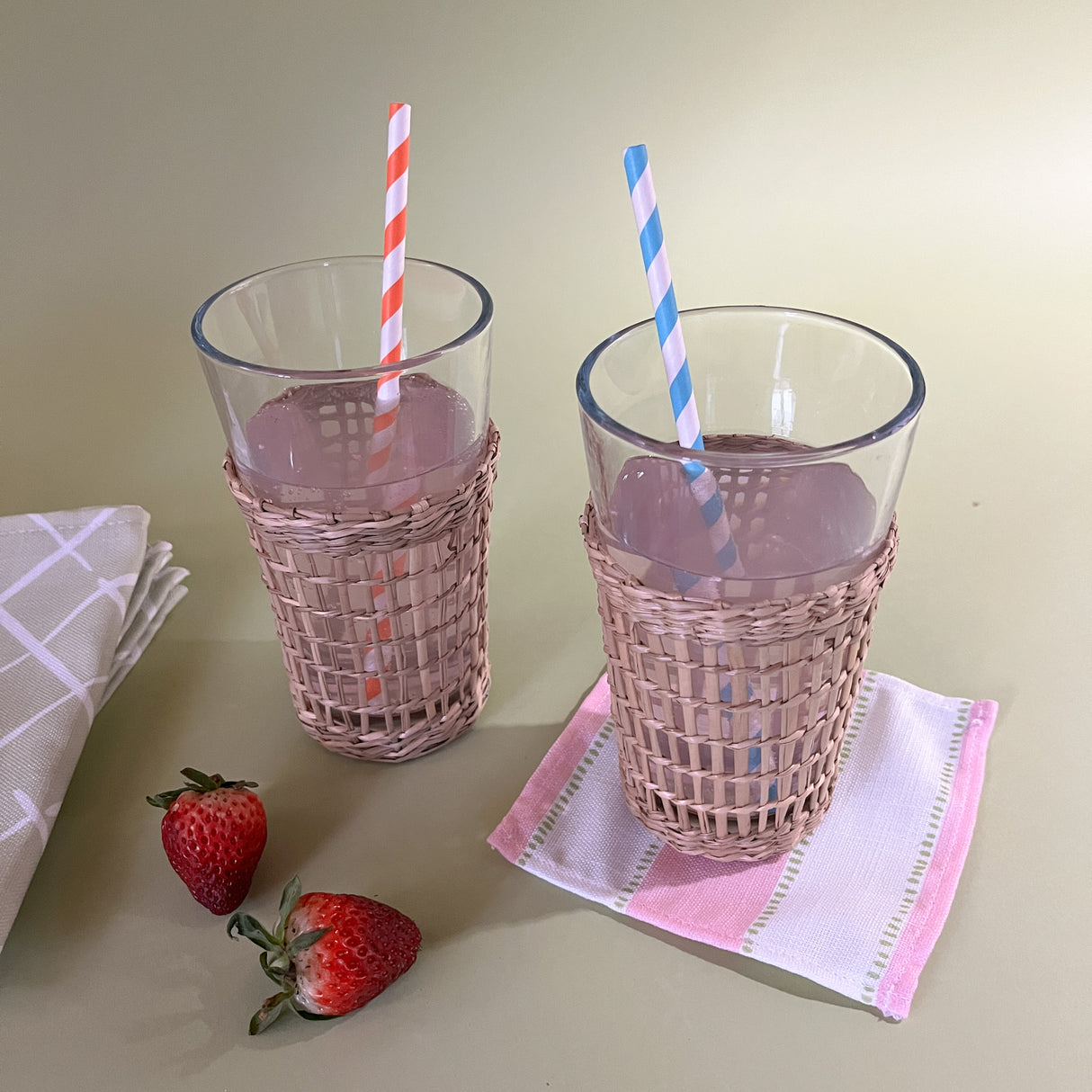 drinking glasses with seagrass sleeve with straws on cocktail napkin