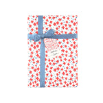 Charming gift wrap featuring vibrant red floral stars, blue accents, and a playful patterned design.