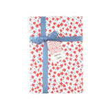 Charming gift wrap featuring vibrant red floral stars, blue accents, and a playful patterned design.