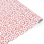 Charming gift wrap featuring vibrant red floral stars, blue accents, and a playful patterned design.