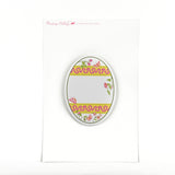 an egg-shaped spring paper place card with a floral and ribbon design on a white background and a pink logo that says Madcap Cottage in the top left corner. 