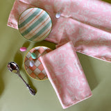 Hampton Court, shell pink cloth dinner napkins with plaid plates, candied eggs on a green background. 