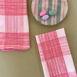 two pink gingham dinner napkins in gin lane print fabric by madap cottage next to a plate with small colored easter eggs