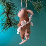 back of one felt mouse ornaments wearing white snowflake costume frame hanging from pine branches