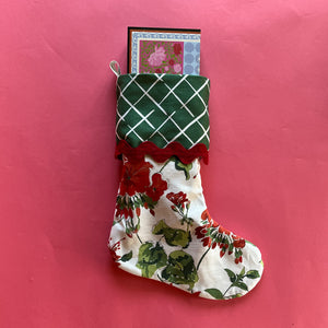 A geranium print red Christmas stocking filled with a notepad