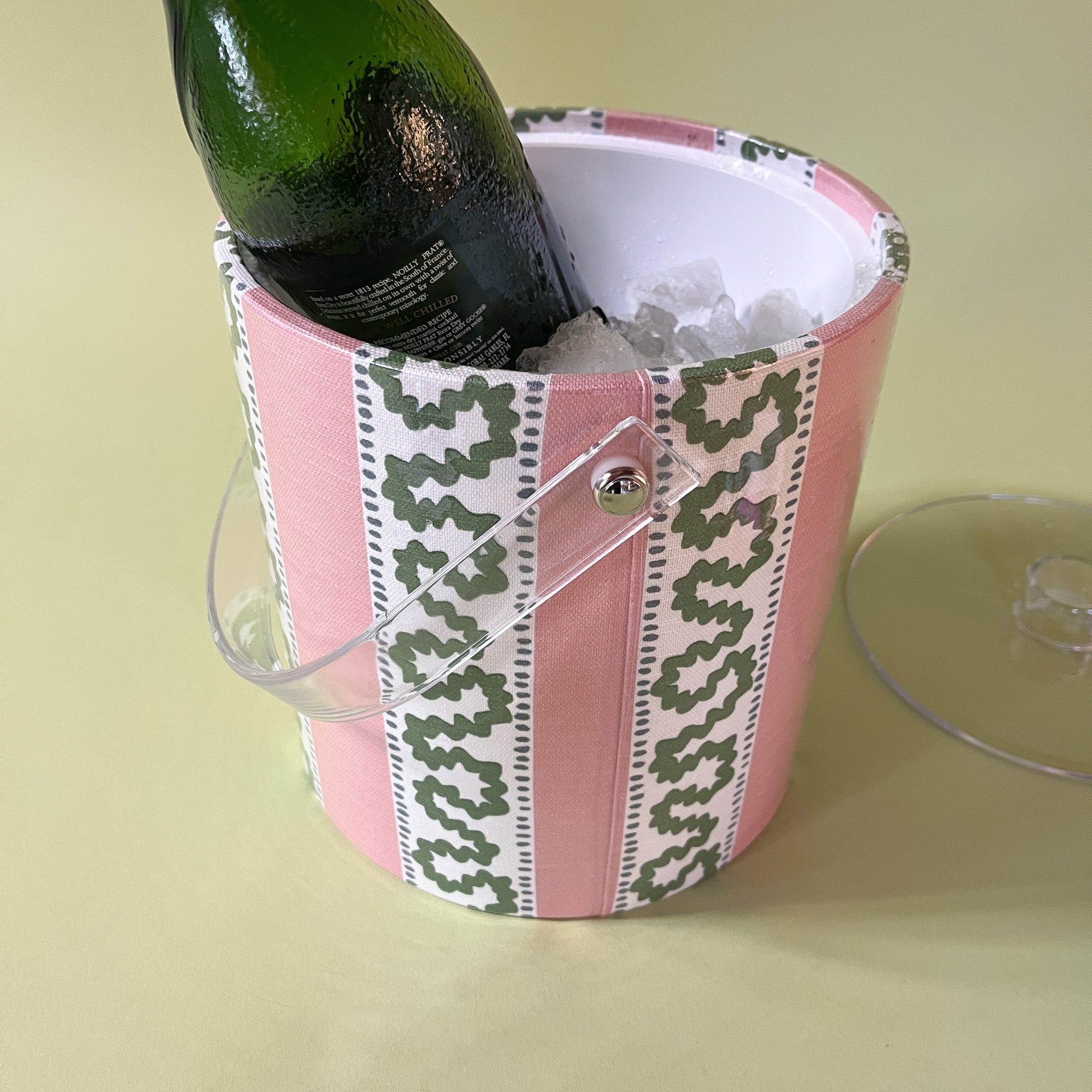 an pink and green acrylic ice bucket filled with ice and a bottle.