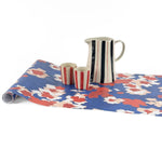 Floral blue red paper table runner styled with striped pitcher and matching cups.