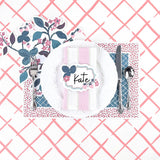 Floral strawberry themed table setting featuring a decorative place card, white dinner plate, patterned placemat, and pink trellis background.