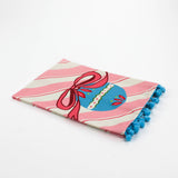 Striped Pink Christmas tea towel with blue pom pom trim folded so that a blue ornament with a pink bow shows 