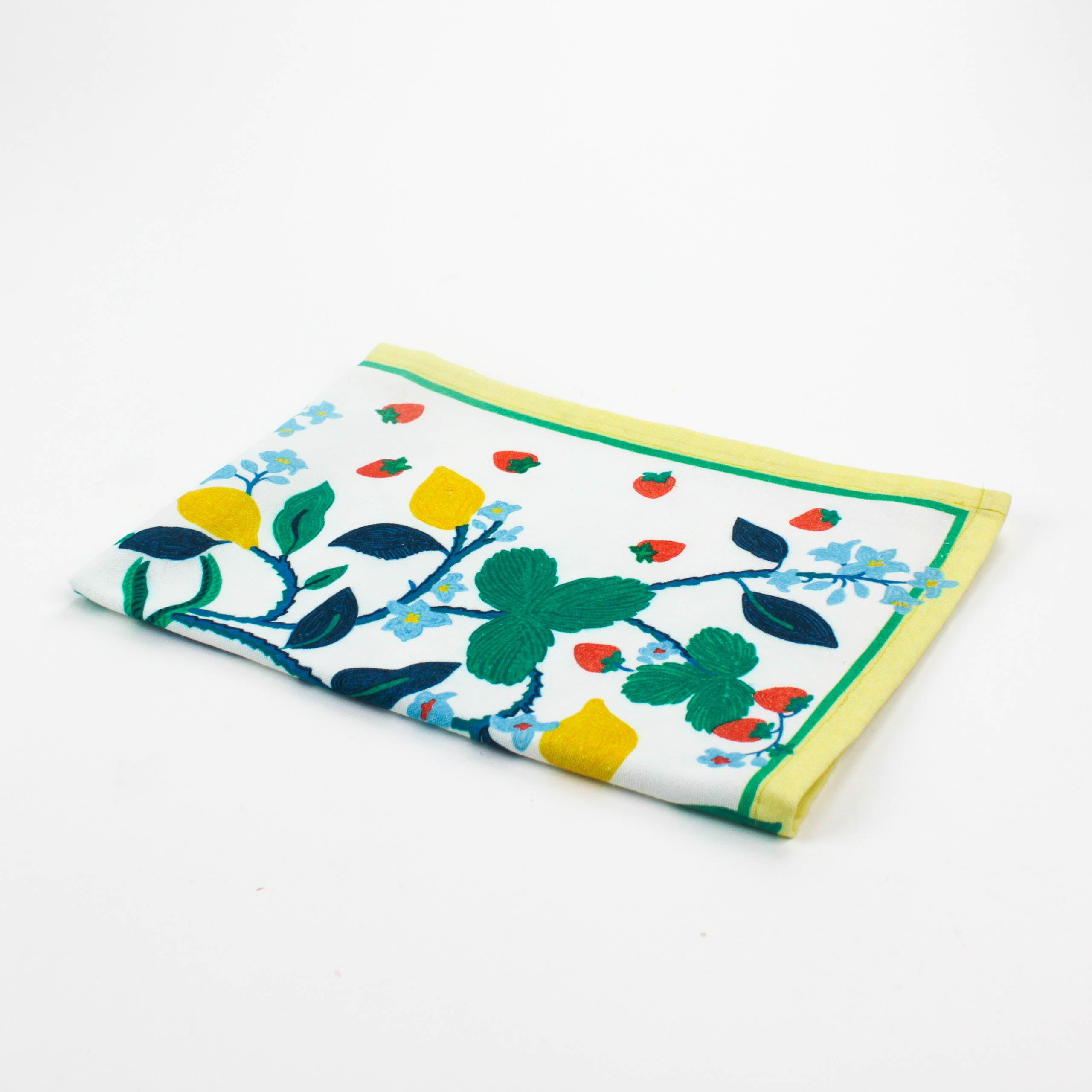 Christmas tea towel featuring a bright botanical design with yellow lemons, red strawberries, and green leaves on a white background bordered with soft yellow and green trim.