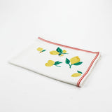 White Christmas tea towel decorated with yellow lemons and green leaves along the edges, bordered by a thin red outline