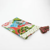 Folded Christmas tea towel featuring a colorful chinoiserie-inspired landscape print with green, pink, and blue tones, finished with a pink and green tassel accent.