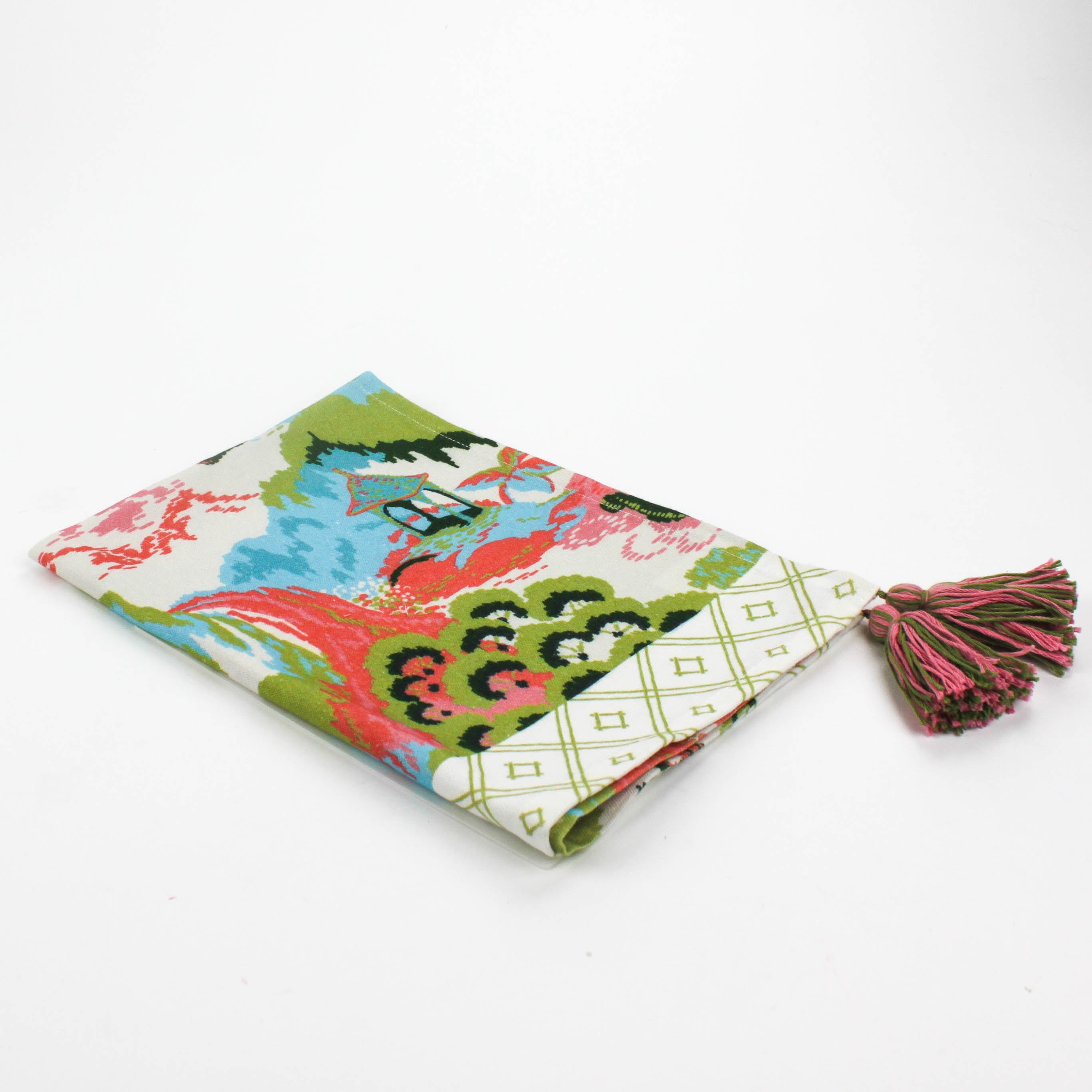 Folded Christmas tea towel featuring a colorful chinoiserie-inspired landscape print with green, pink, and blue tones, finished with a pink and green tassel accent.