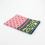 Christmas tea towel featuring a pink lattice pattern with green and white Chinoiserie-inspired borders