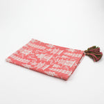 Half-folded Christmas tea towel with a pink and white chinoiserie pagoda pattern, featuring intricate architectural motifs and pink-green tassels on each corner.