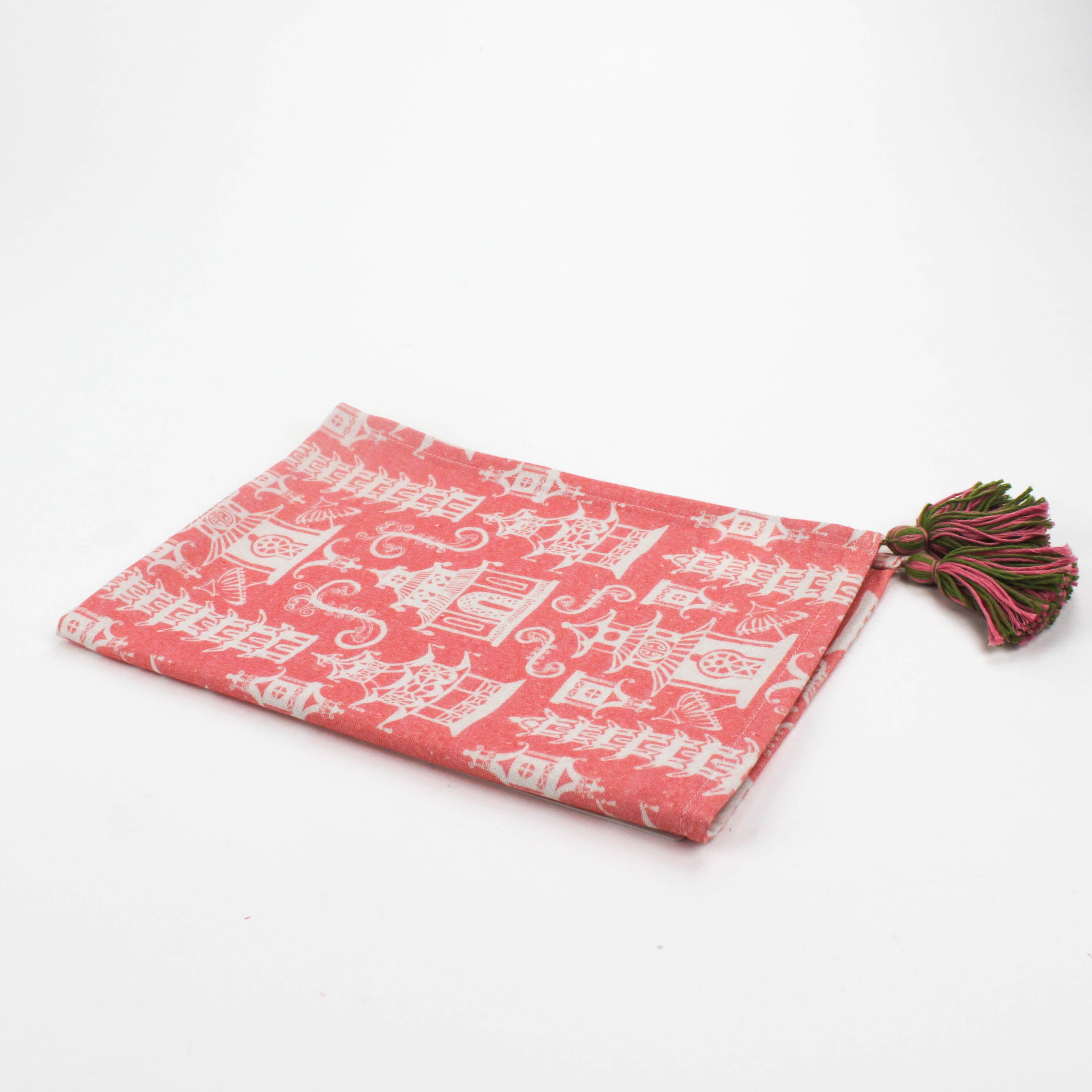 Half-folded Christmas tea towel with a pink and white chinoiserie pagoda pattern, featuring intricate architectural motifs and pink-green tassels on each corner.