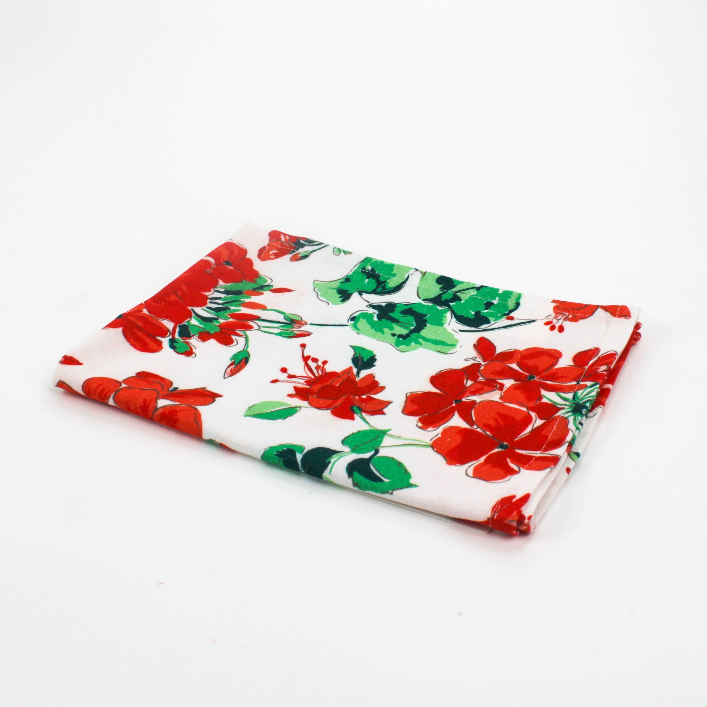 Folded Christmas tea towel featuring a festive red geranium floral print with green leaves on a white background, creating a bright holiday-inspired design.