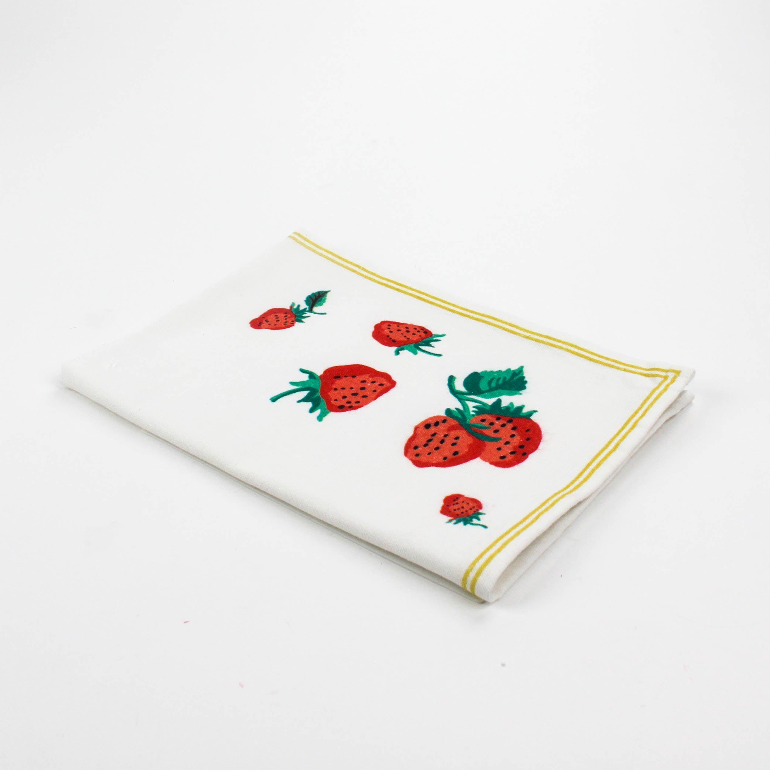 Folded Christmas tea towel with a white background, decorated with strawberries and green leaves in one corner, bordered by a thin yellow trim.