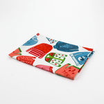 Folded christmas tea towel with colorful holiday sweater pattern in red, green and blue on a white background