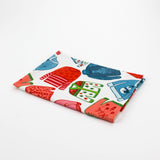 Folded christmas tea towel with colorful holiday sweater pattern in red, green and blue on a white background