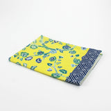 Christmas tea towel with a bright yellow background featuring a blue and green floral chinoiserie pattern