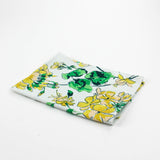 Christmas tea towel with a cheerful yellow and green floral geranium pattern on a white background