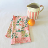a folded pink chinoiserie tea towel from madcap cottage with pug and vase motifs.