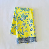 a folded yellow chinoiserie tea towel with blue cherry blossom motifs.