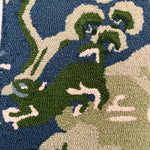 a close up showing the foo dog on a blue and green rug with chinoiserie boatmen and pagoda motifs from madcap cottage.