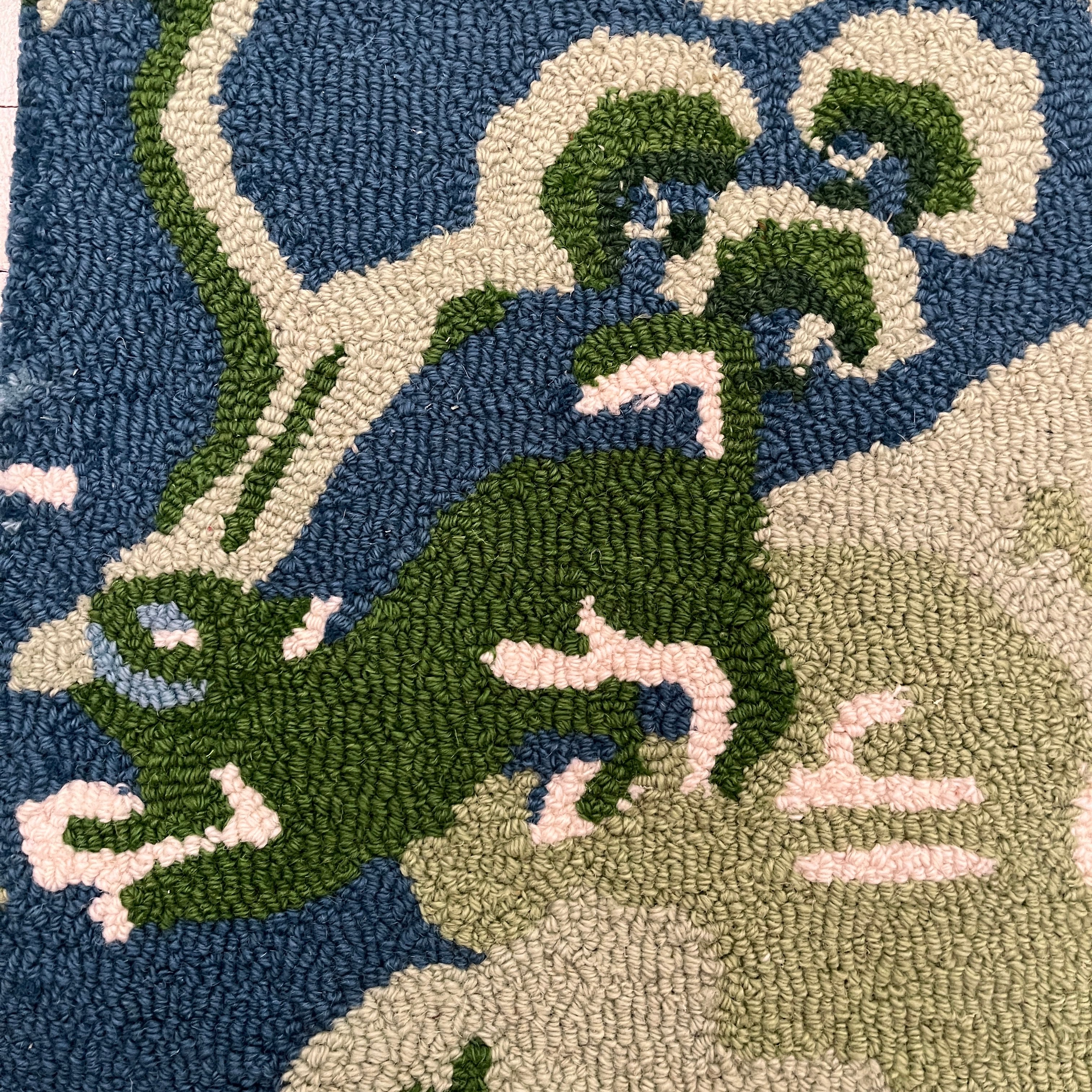 a close up showing the foo dog on a blue and green rug with chinoiserie boatmen and pagoda motifs from madcap cottage.