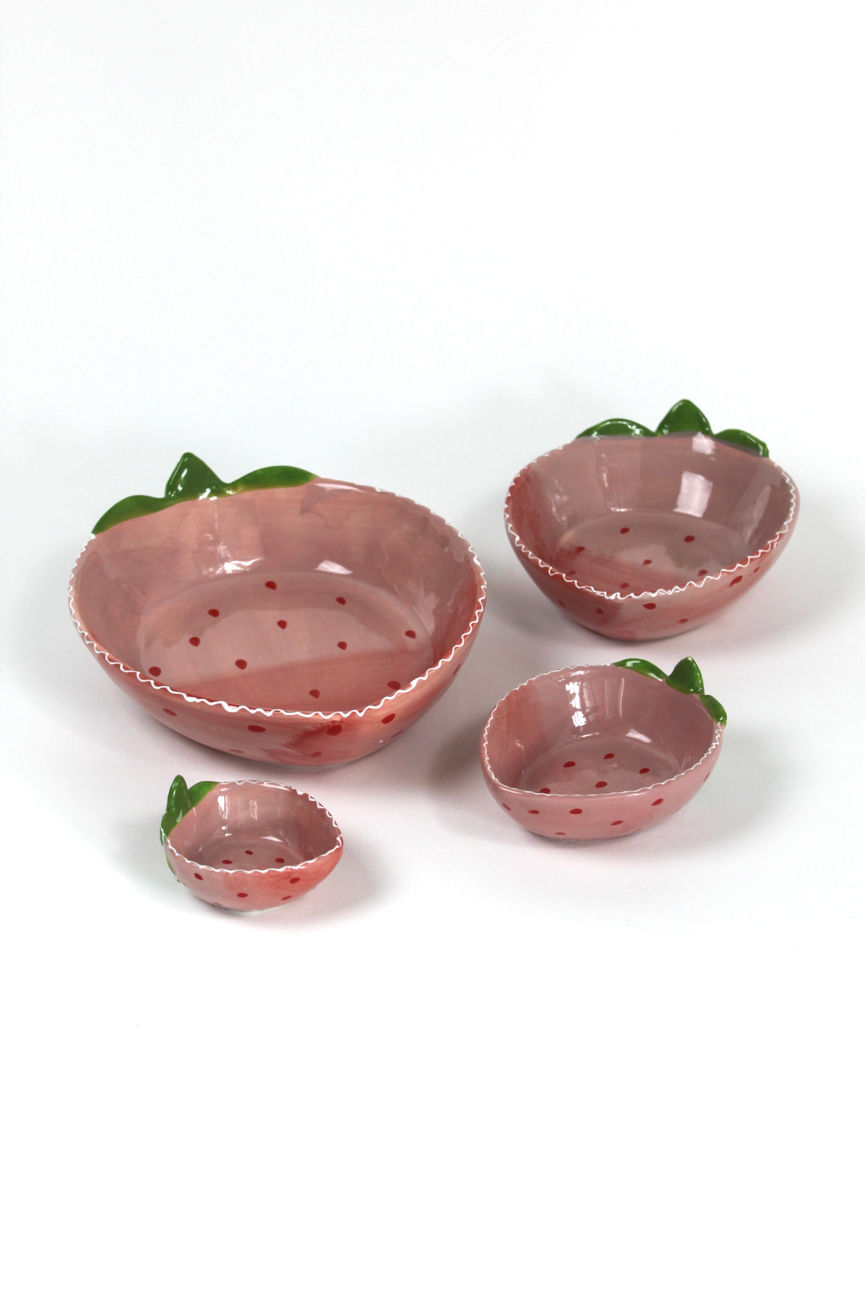 a set of four pink ceramic strawberry dishes in graduating sizes.
