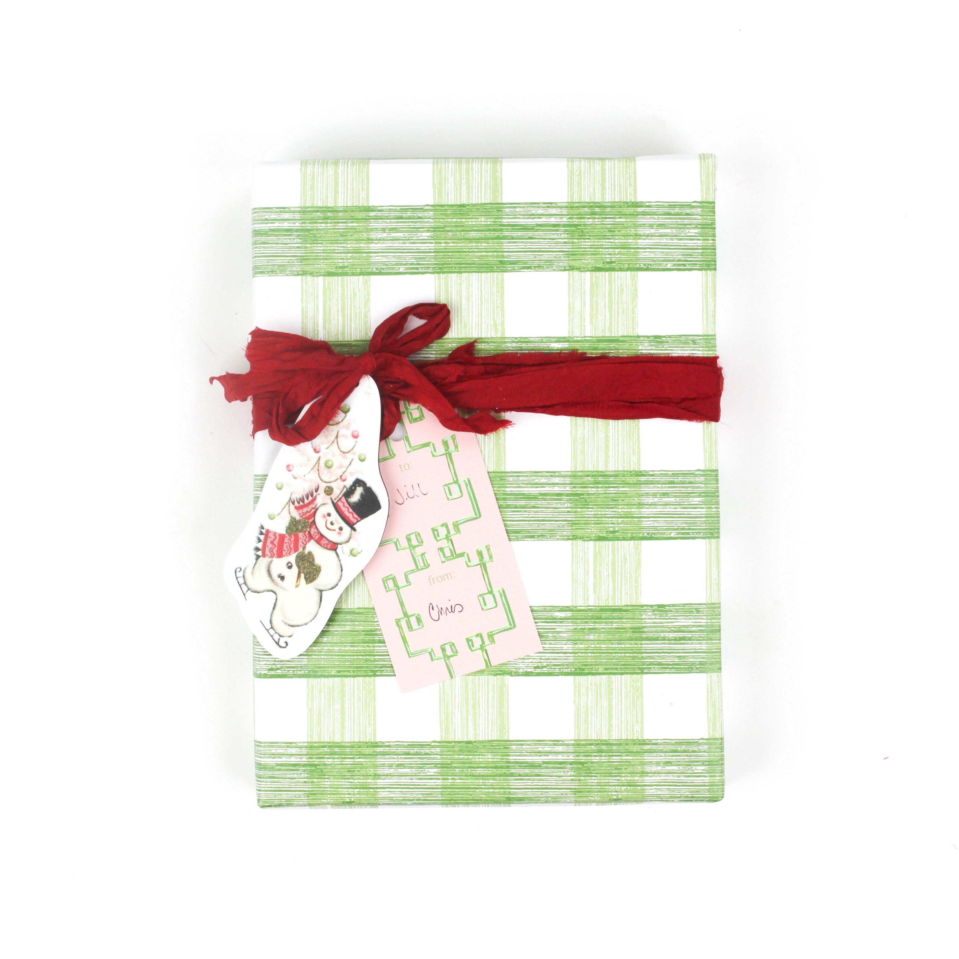 Green gingham gift wrap styled with red ribbon and holiday gift tags.