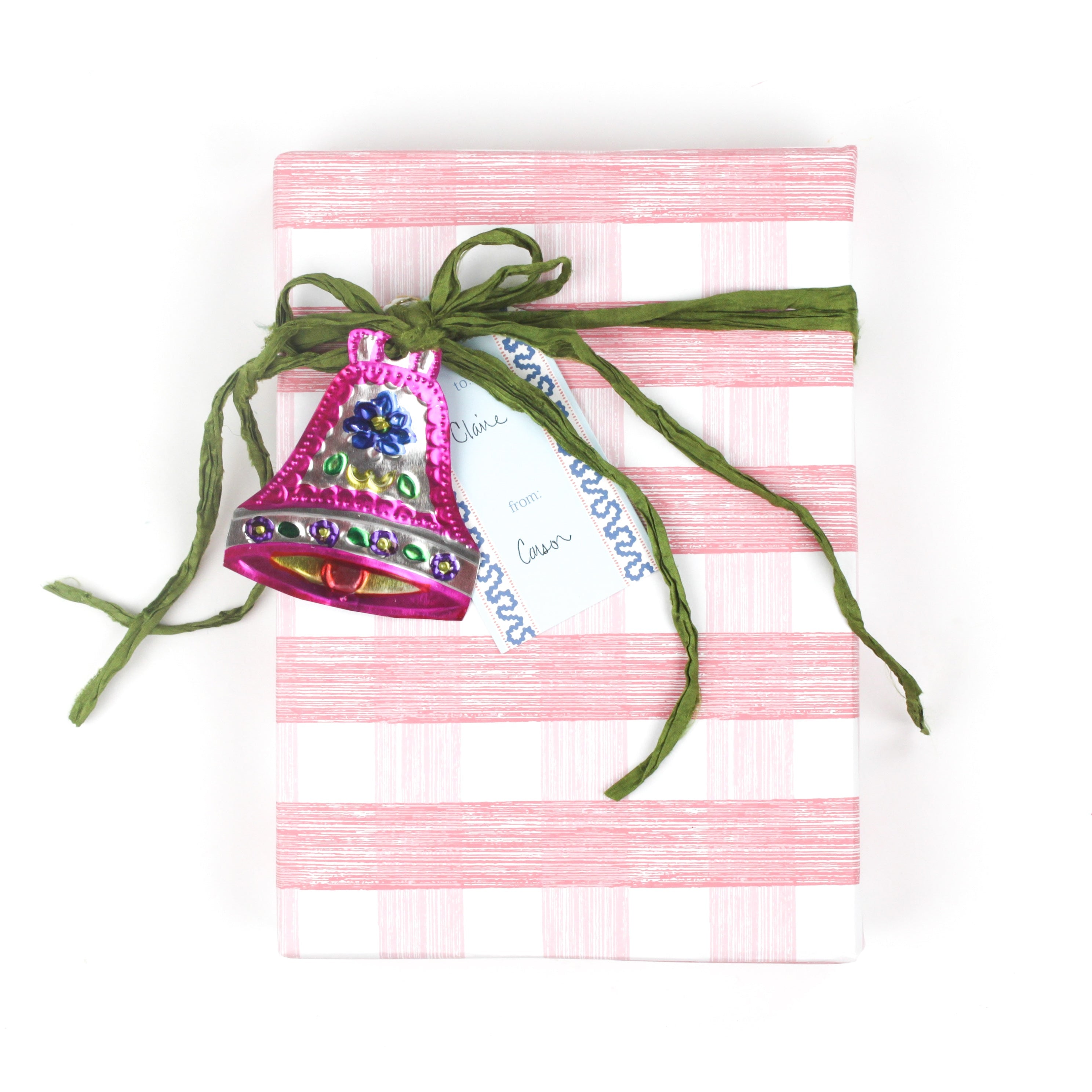 Gift wrapped in pink gingham-style wrapping paper with green ribbon and pink bell ornament.